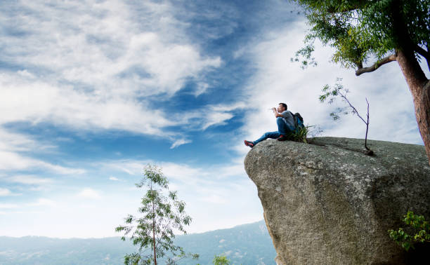istock Hiking man sitting on the rock drinking water 957329136