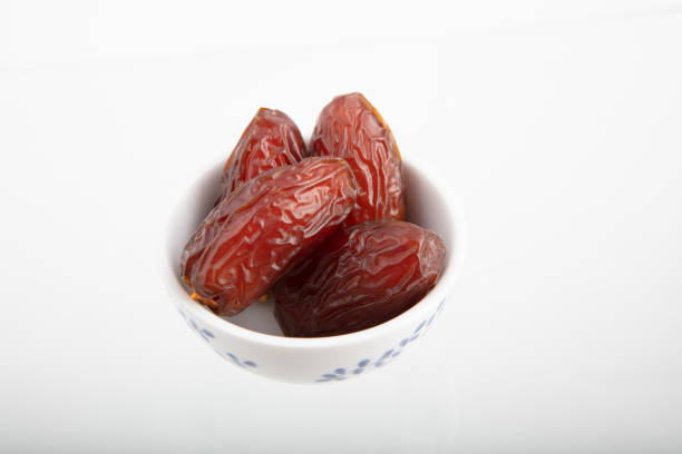 Dried date fruit in bowl on white background , high angle view high quality image