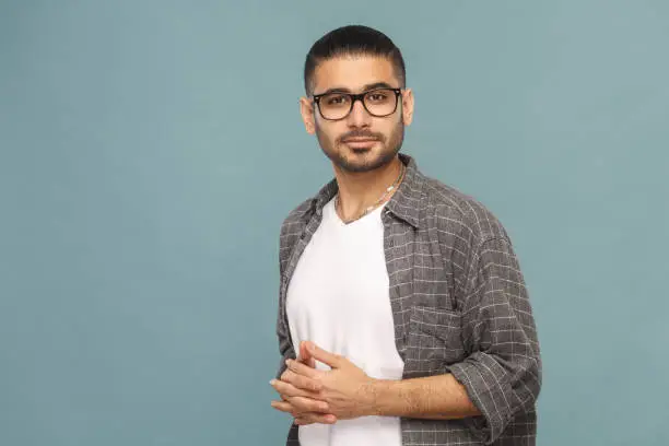 Portrait of bearded handsome man with black glasses in casual style looking at camera and smiling. studio shot on blue background.