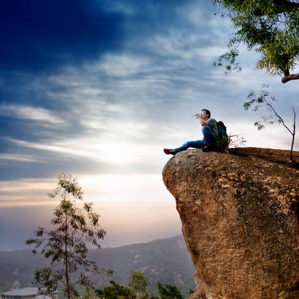 istock Hiking man sitting on the rock drinking water 957339826
