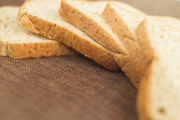 istock Pile slice of whole wheat bread on dark brown calico 957344178
