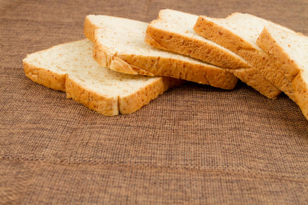 istock Pile slice of whole wheat bread on dark brown calico 957344836