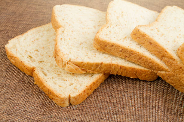 istock Pile slice of whole wheat bread on dark brown calico 957344866
