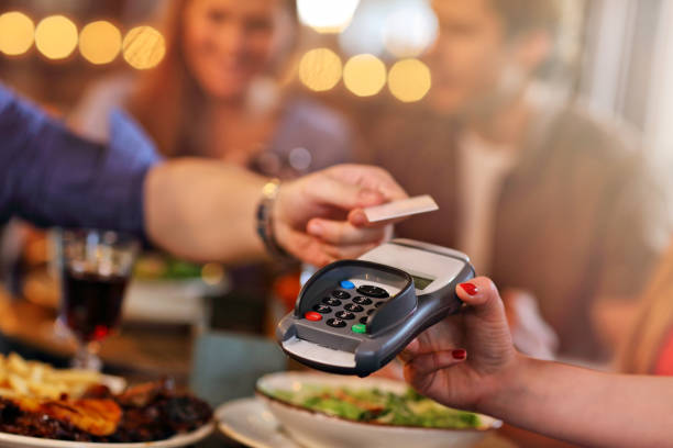 Group Of Friends Paying For Meal In Restaurant stock photo