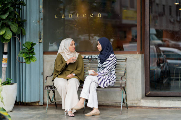 Friends sitting outside drinking coffee and chatting. Kuala Lumpur, Malaysia.