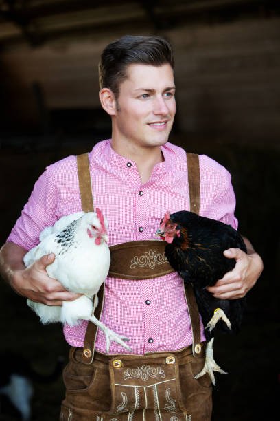 istock young bavarian man holding two chickens 957345944