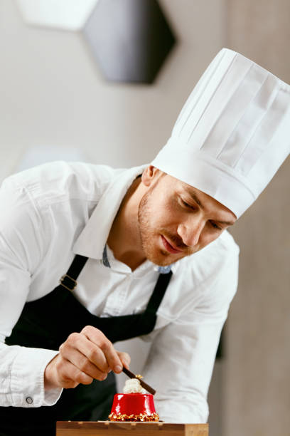 istock Male Pastry Cook Decorating Dessert In Kitchen 957352342