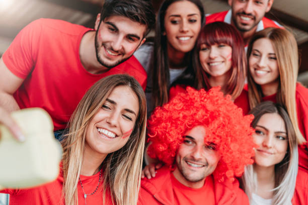 istock Fans at stadium together taking selfie with instant print camera 957360442