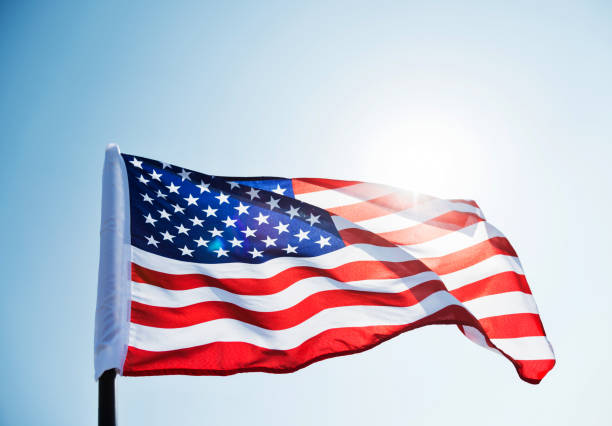 amerikanische flagge winken gegen blauen himmel - flag american culture flying sky stock-fotos und bilder