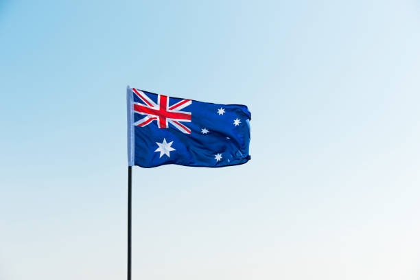 Waving Australia flag against blue sky.