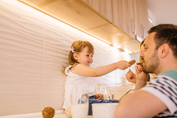 istock Young daughter is feeding her father with cookies 957366060