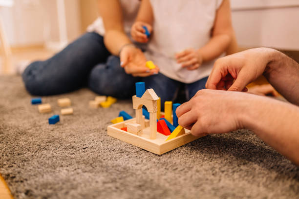 istock Parents with daughter playing wooden puzzle game 957366122
