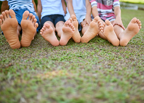 Cropped shot of a group of kids sitting barefoot on grass