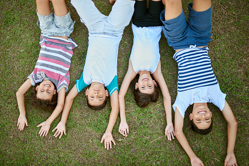 High angle portrait of a group of happy siblings lying together on the grass