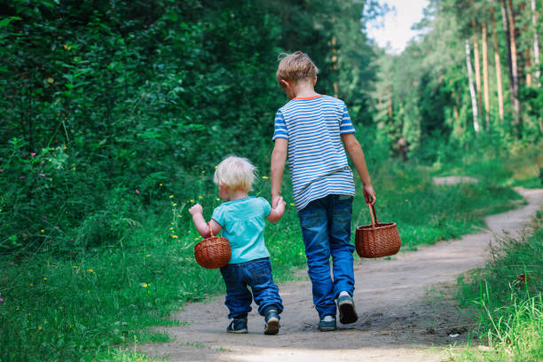 istock little boy and girl going to forest 957369352