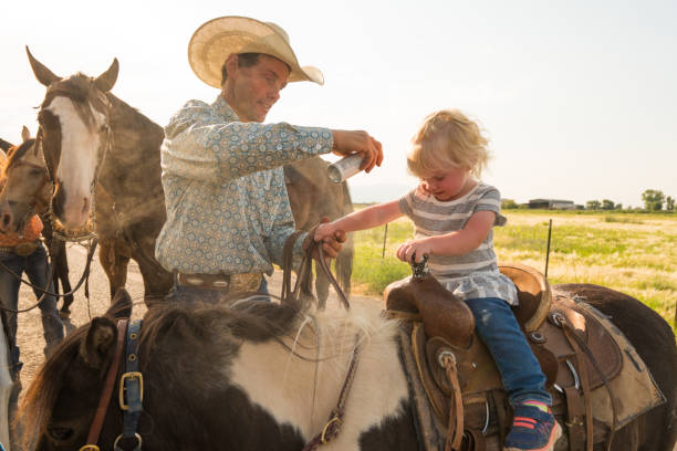 istock Father applying sun screen and bug spray to child on horse. 957369964