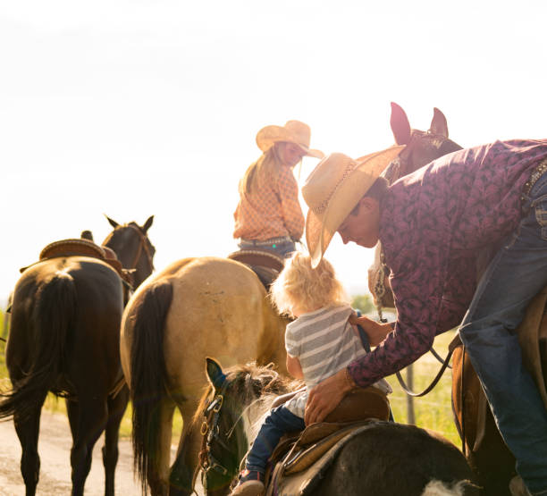 istock Parent preparing horse for child to ride. 957370094