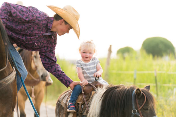 istock Young cowboy leading a small girl on horseback. 957370310