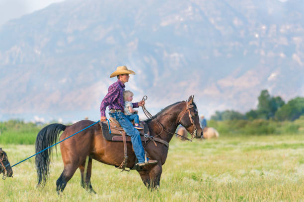 istock Young cowboy leading a small girl on horseback. 957370384