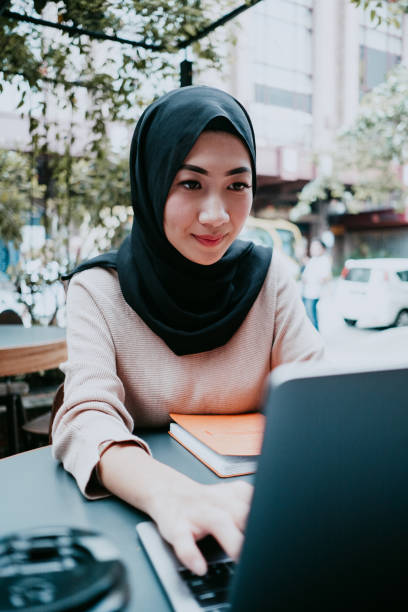 istock asian woman smiling at laptop, working 957372888