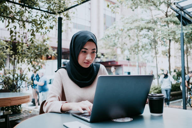 istock woman with hijab looking at laptop, working 957373006