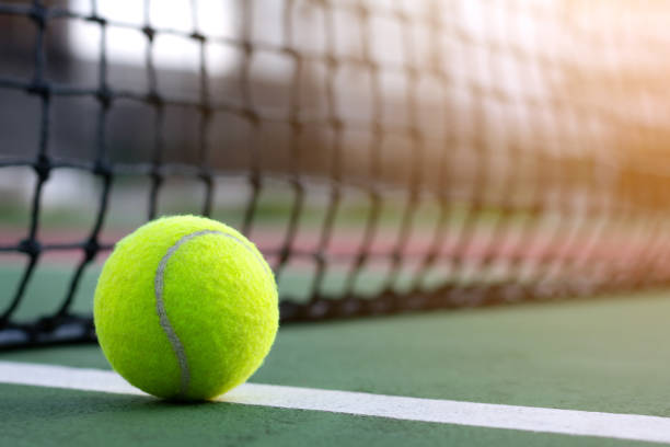 istock Close up tennis ball on blur net with copy space 957379210