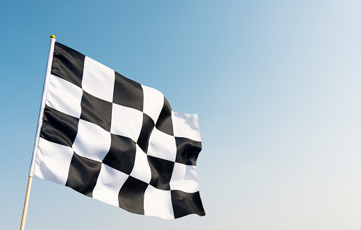 Checkered flag flying on blue sky