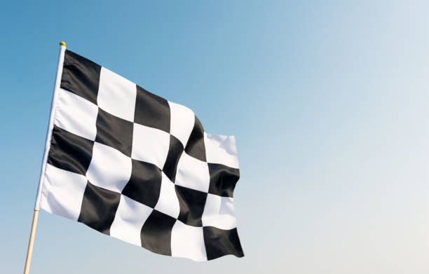 Checkered flag flying on blue sky Checkered flag flying on blue sky street racing stock pictures, royalty-free photos & images