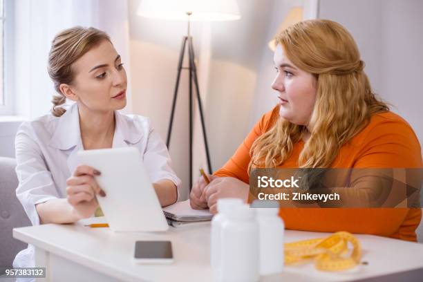 Serious Skilled Nutritionist Talking With A Stout Woman Stock Photo - Download Image Now