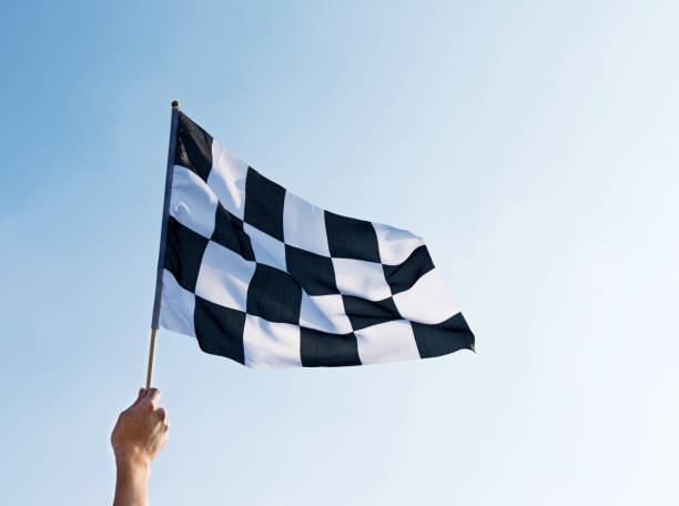 istock Man hand holding checkered flag in the wind 957383158