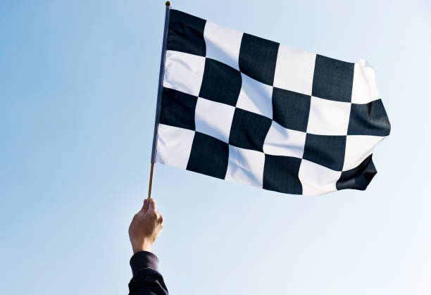 istock Man hand holding checkered flag in the wind 957383196
