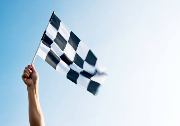istock Man hand holding checkered flag in the wind 957383250