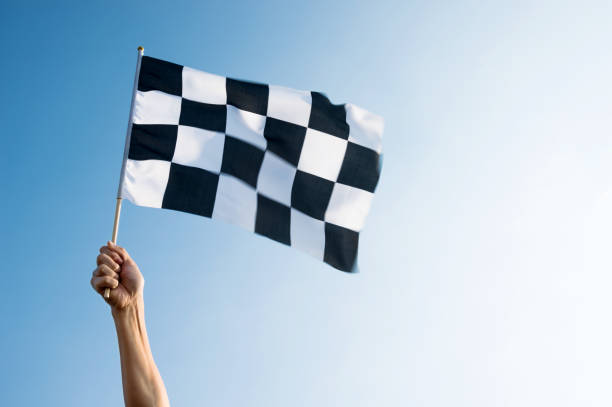 istock Man hand holding checkered flag in the wind 957383286