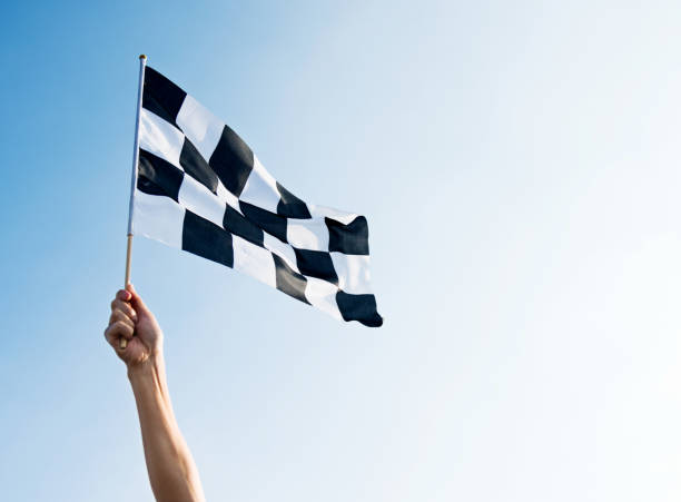 istock Man hand holding checkered flag in the wind 957383292