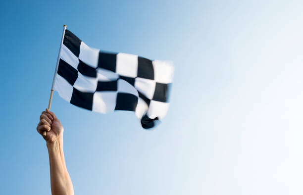 istock Man hand holding checkered flag in the wind 957383340