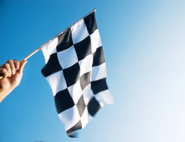 istock Man hand holding checkered flag in the wind 957383400