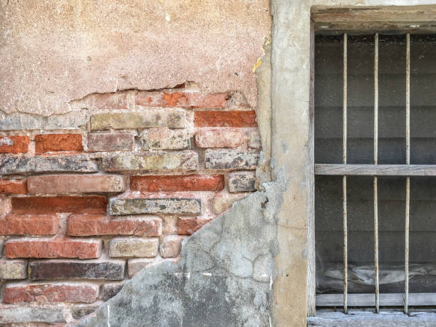 istock old rustic wood frame with metal bar and glass louver in cracking brick wall close-up 957384498