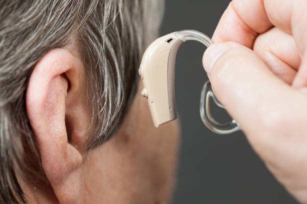 istock Closeup senior woman using hearing aid 957389280