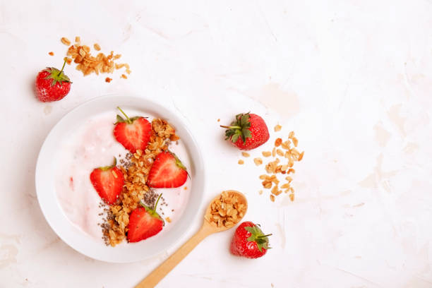 Wooden smoothie bowl, assorted ingredients on table. Healthy nutritious breakfast with vegan yogurt, raw fruits, nuts and cereals.