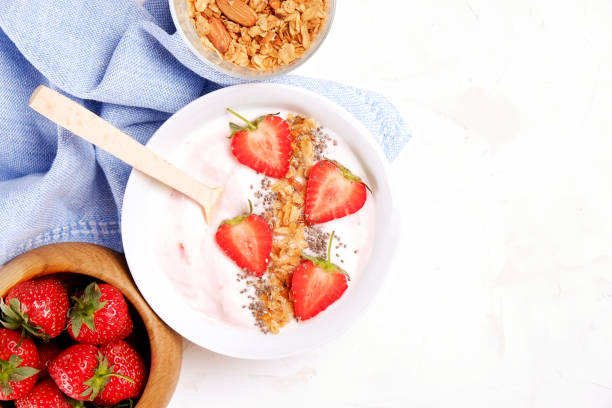 istock Wooden smoothie bowl, assorted ingredients on table. Healthy nutritious breakfast with vegan yogurt, raw fruits, nuts and cereals. 957389384