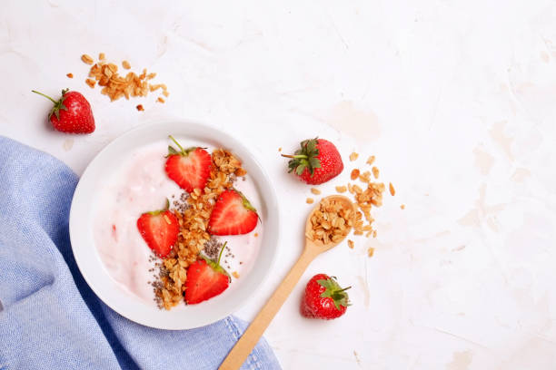 istock Wooden smoothie bowl, assorted ingredients on table. Healthy nutritious breakfast with vegan yogurt, raw fruits, nuts and cereals. 957389386