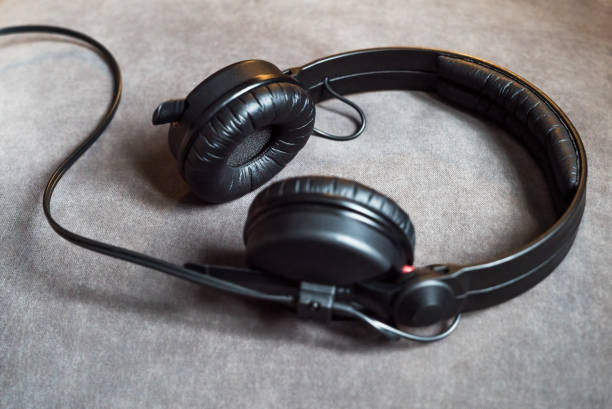 istock Black audio hipster headphones with cord lying on grey background 957389478