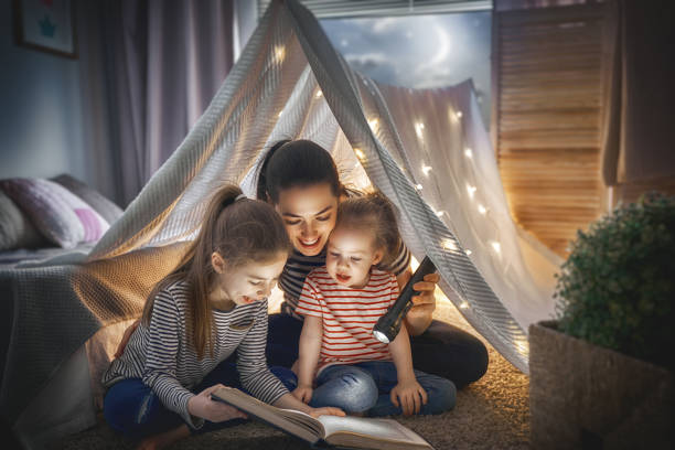 istock Mom and children reading book 957393878