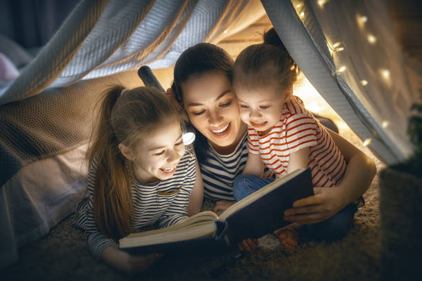 istock Mom and children reading book 957394152