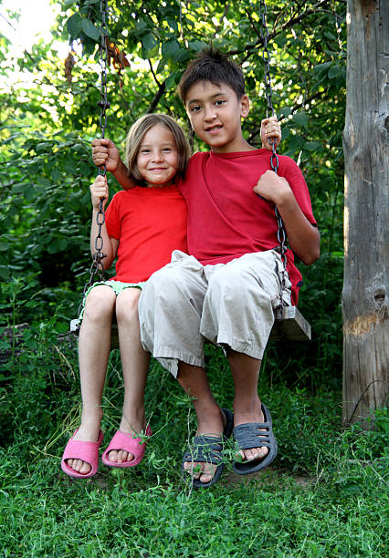 istock boy and girl on swing 95739672