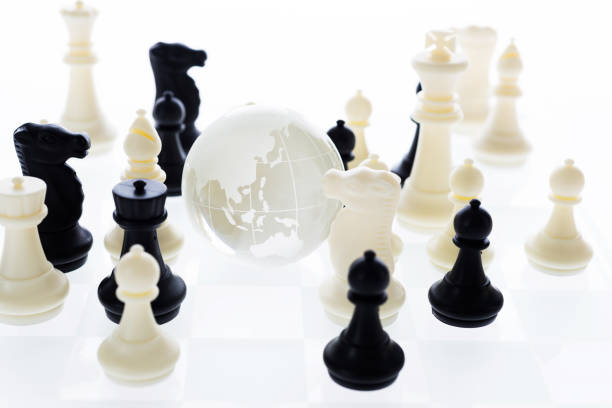 istock Chess pieces and glass earth globe on the board 957396976