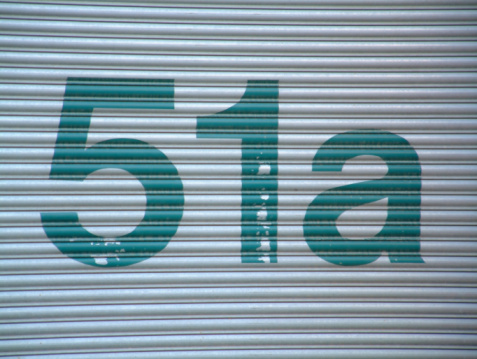 Large worn green 51a on a corrugated door.