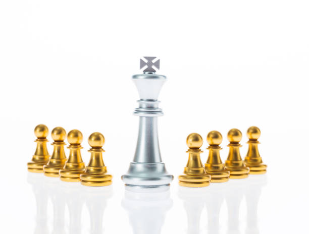 istock Silver king and golden pawns in a white background 957397774