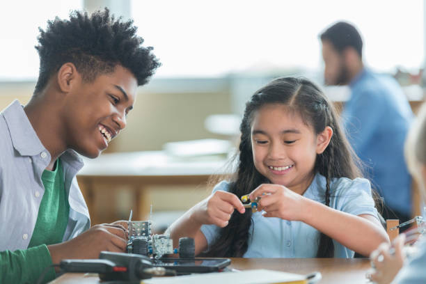 istock High school student helps girl in engineering club 957408106