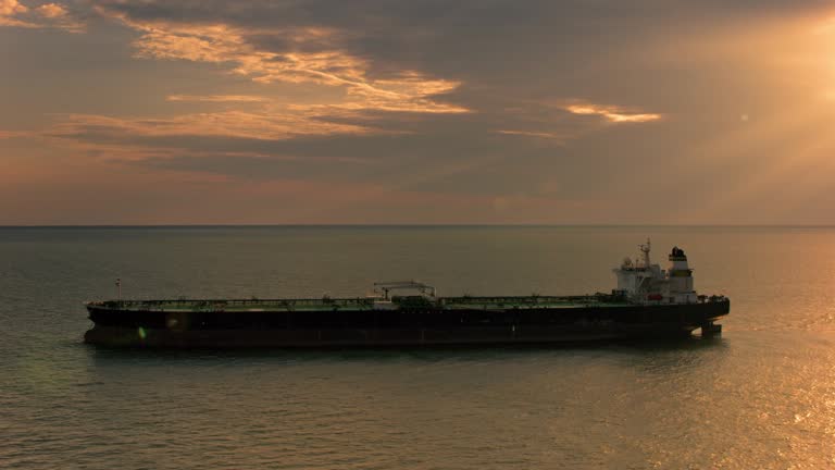 AERIAL Cargo ship at sea as sun is peeking through dark clouds